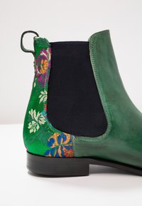Botines Chelsea verdes con parte superior de cuero texturizado, acentos de tela floral, paneles laterales elásticos y una suela negra elegante.