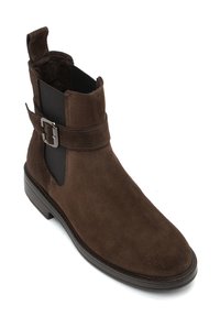 Brown suede ankle boot with elastic side panels, adjustable metal buckle detail, and a rounded toe. Flat rubber sole for stability.