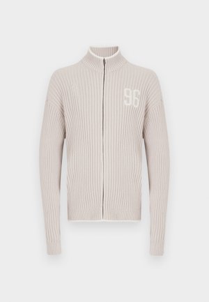 Helebeežikarva soonikuga lukuga kampsun kõrge kraega. Vasakul rinnal on tagasihoidlik valge number "96", tekstuurse kudumi ja tihendatud varrukasäärtega.