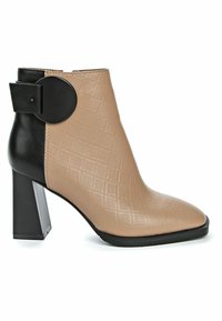 Botín beige de tacón con textura acolchada, tacón negro y detalle circular. Presenta punta puntiaguda y acabado en cuero liso.