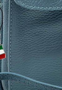 Blauwe leren handtas met een gestructureerd oppervlak, voorzien van een metalen bedel in de vorm van de Italiaanse vlag in groen, wit en rood.