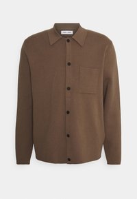 Chemise boutonnée marron en tissu doux, avec un col classique, des boutons noirs et une poche poitrine sur le côté gauche.
