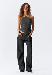 Čierny top na ramienka so subtilnými trblietkami a textúrovanými širokými nohavicami v čiernej farbe. Odev má priliehavý strih a hladký materiál.