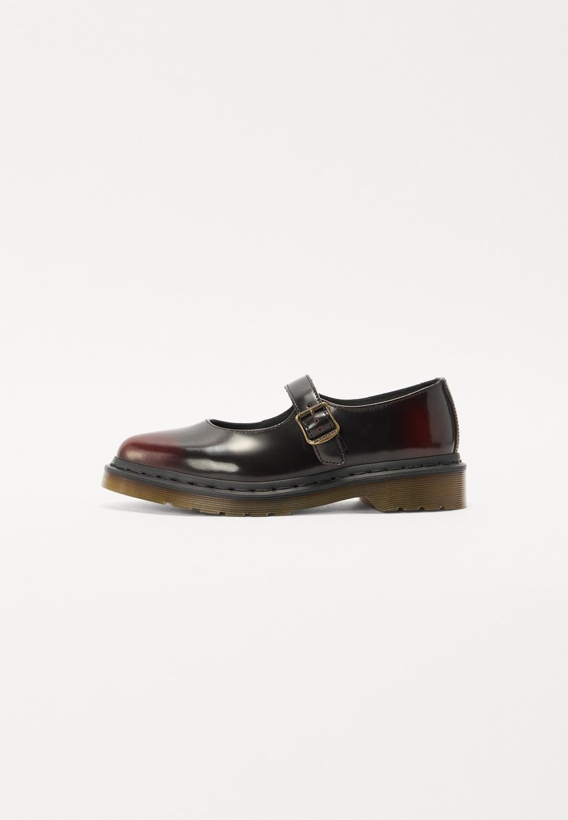 Chaussure Mary Jane noire brillante avec une semelle en caoutchouc translucide marron et une bride à boucle dorée sur le dessus du pied sur fond blanc.