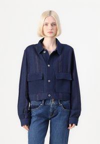 Κοντό τζάκετ από ναυτικό τζιν με κολλεγιακή γιακά, κλείσιμο με κουμπιά, δύο μπροστινές τσέπες και κατακόρυφες ρίγες κατά μήκος των μανικιών. Λαμπερή υφή.