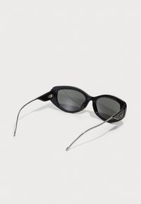 Black sunglasses with a sleek glossy plastic frame, oval lenses, and slender silver metal arms featuring a small logo detail.