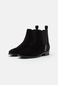 Bottines en daim noir avec panneaux latéraux élastiques, languettes de tirage et petit talon bloc. Présentent un design élégant au style minimaliste.