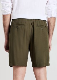 Olivgrüne Shorts mit entspanntem Schnitt, elastischem Bund und zwei Gesäßtaschen mit Knopfverschluss. Weicher Stoff und knielanges Design.
