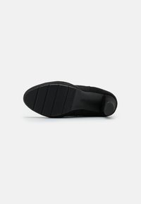 Suola di scarpa in suede nero con battistrada in gomma testurizzata, caratterizzata da scanalature segmentate per una maggiore aderenza e un design elegante e minimalista.