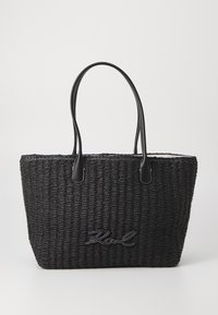 Black woven tote bag with leather handles, featuring a textured surface and embroidered logo detail on the front.
