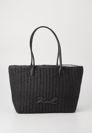 Sac cabas tissé noir avec poignées en cuir, présentant une surface texturée et un logo brodé sur le devant.