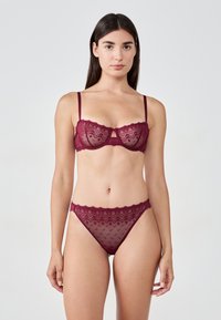 Burgundy lace lingerie set featuring a sheer bra with keyhole detail and matching bikini briefs with scalloped edges and geometric patterns.