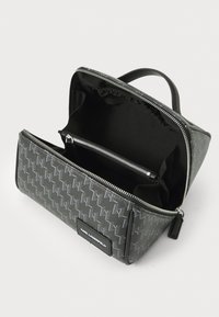 Grå mønstret kosmetikkveske med glidelås, håndtak og flere innvendige rom for organisering. Tekturert syntetisk materiale.