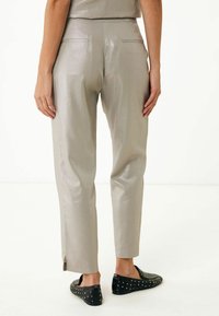 Ljusgrå, texturerade byxor med slim fit, som har två bakfickor och en sidoklyvning i fållen, tillsammans med svarta nitarprydda slip-on-skor.