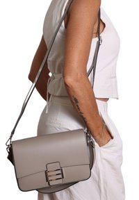 Borsa a tracolla in pelle grigia con una forma strutturata, dotata di una chiusura metallica e di una tracolla regolabile. Texture liscia e design minimalista.