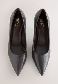 Paire d'escarpins pour femmes à bout pointu de couleur marron foncé texturée avec la marque "NEXT Forever Comfort" à l'intérieur.