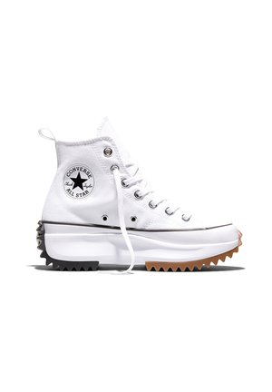 Weißer High-Top Converse Sneaker mit dicker, gezackter zweifarbiger Sohle, Metallösen und schwarzem Stern-Logo-Patch an der Seite.