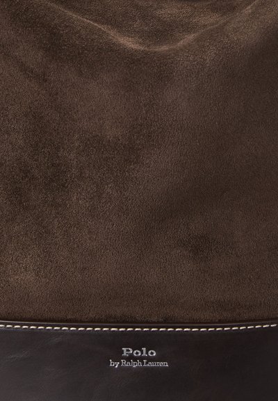 Ruskea mokkabag, jossa on sileä nahkapohja. Ominaisuudet valkoisessa ompelussa ja logotarrassa alemmassa osassa. Pehmeä pinta ja monipuolinen muotoilu.
