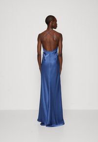 Rochie de seară din satin, de culoare albastru închis. Prezintă un decolteu adânc pe spate, bretele subțiri încrucișate și o siluetă ajustată cu fustă vaporos. Fără aplicații vizibile.