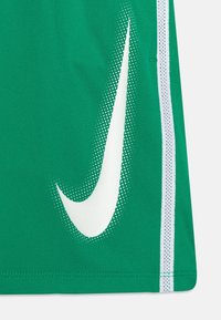Grüne Sportshorts mit großem weißen Nike Swoosh-Logo in gepunkteter Textur, ergänzt durch weiße Seitenstreifen. Hergestellt aus leichtem Stoff.