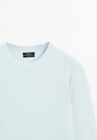 Ljusblå kasmirtröja med ribbad rund halsringning och slät textur, med varumärkesetikett synlig vid halsområdet.