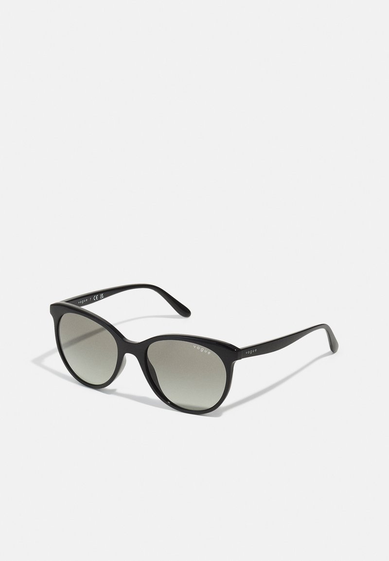 Ochelari de soare ovali negri cu lentile gradient, cadru din plastic și brațe subțiri. Prezintă marca "vogue" pe tample.