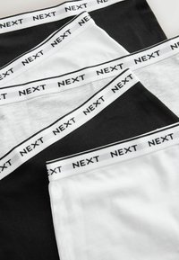 Sous-vêtements en coton noir et blanc. Dotés d'une taille élastique avec "NEXT" imprimé en noir sur fond blanc. Texture douce.