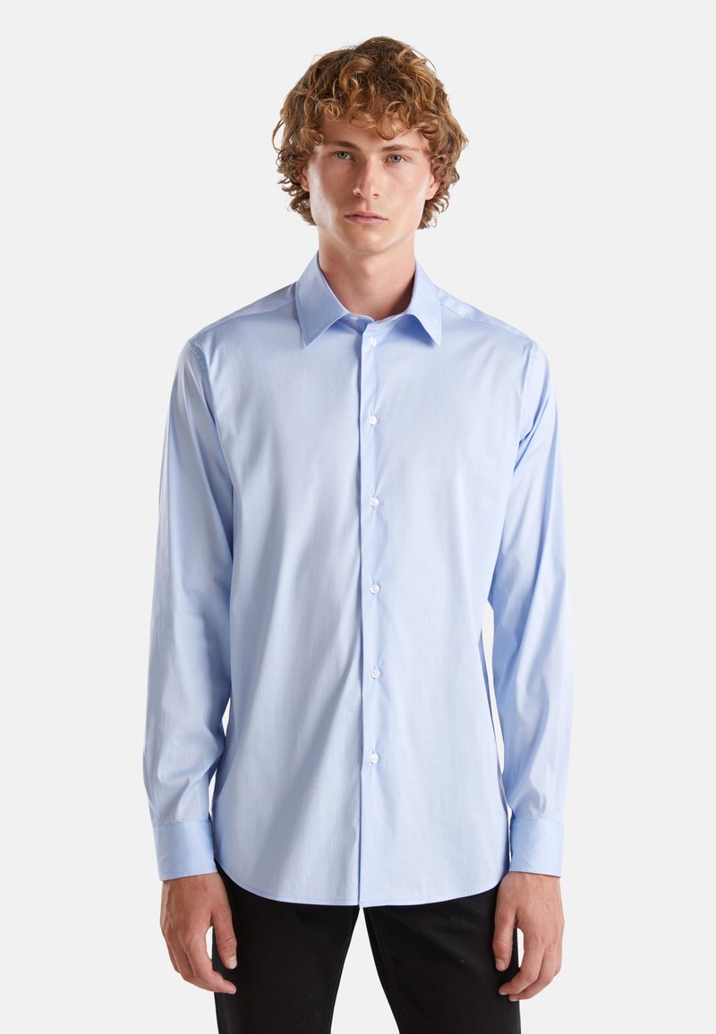 Camicia button-up a maniche lunghe di colore azzurro chiaro, realizzata in tessuto morbido, con colletto classico e sei bottoni frontali, dal taglio adattato.