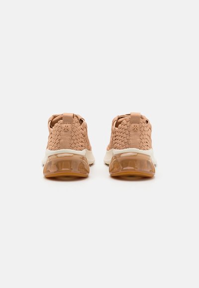 Beige-gewebte Sneakers mit einer strukturierten Oberseite, ausgestattet mit einem gepolsterten Kragen und einer transparenten Gummisohle. Die Rückansicht zeigt das Detail der Zuglasche.