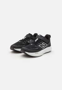 Baskets de sport noires avec dessus en mesh, accents blancs, sangle ajustable et semelle texturée. Présente un logo et un design respirant.