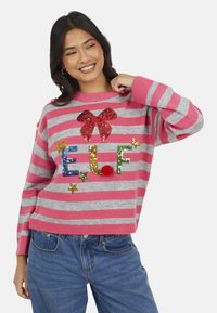 Pull rayé rose et gris doté d'un nœud rouge en sequins, d'ornements colorés "E.L.F." et d'accents étoilés. Tissu tricoté doux, coupe décontractée.