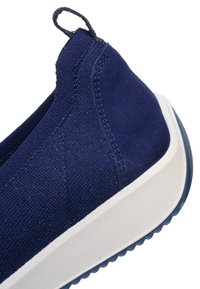 Tmavě modrá teniska na nazutí s texturovanou pletenou látkou, semišovou patní částí, látkovou poutkou a silnou bílou gumovou podrážkou s vzorovaným běhounem.