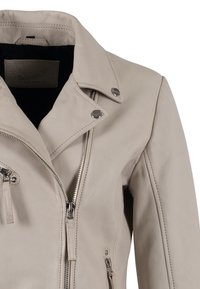Giacca da motociclista in pelle beige chiaro con hardware argentato, zip frontale e colletto asimmetrico. Dotata di tasche con zip e finitura testurizzata.