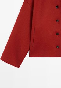 Cappotto di lana rosso con una finitura testurizzata, caratterizzato da un taglio dritto, maniche lunghe, bottoni neri e una tasca laterale a sinistra.