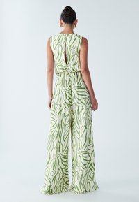 Tuta con motivo verde e bianco, senza maniche, con apertura sulla schiena e gambe larghe, realizzata in tessuto liscio e leggero.