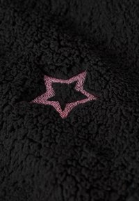 Svart fleece-tyg med en texturerad yta och en framträdande rosa stjärnformad brodering i mitten. Mjukt och plyschigt.