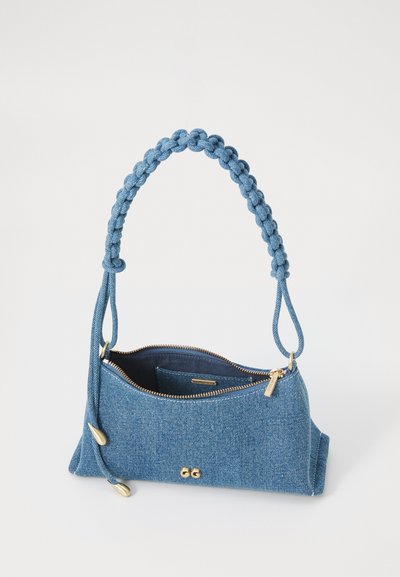 Denim håndtaske med et flettet blåt håndtag, guld lynlås og en trekantet form. Indvendigt har den en lille lomme og en glat tekstur.
