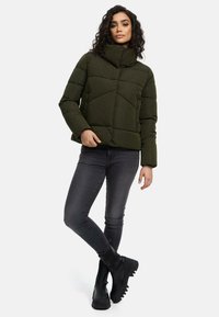 Puffer jacket in dark green with a high collar and quilted design. Paired with fitted dark jeans and black ankle boots.