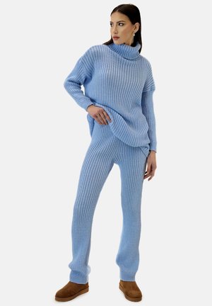 Lichtblauwe geribbelde gebreide trui en bijpassende broek, met een hoge col, een relaxte pasvorm en een zachte textuur. Bruine schoenen maken de look compleet.