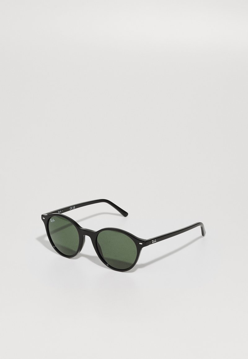 Ochelari de soare din plastic negru, cu lentile verzi rotunde. Caracteristici includ tampoane subtile pentru nas și branding pe bradă. Design curat și minimalist.
