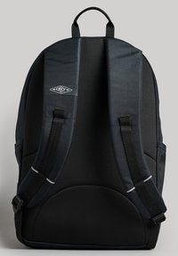 Zaino nero realizzato in tessuto resistente, dotato di spallacci imbottiti, superficie testurizzata e un piccolo logo sulla parte anteriore.