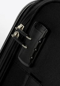 Černý kufr s texturovanou tkaninou, vybavený zipem a kombinovaným zámkem se třemi kolečky. Doplňky zahrnují stříbrné kování.