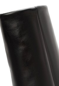 Sedia in pelle nera con uno schienale dalla finitura liscia e lucida; presenta bordi arrotondati e cuciture minime; design elegante e contemporaneo.