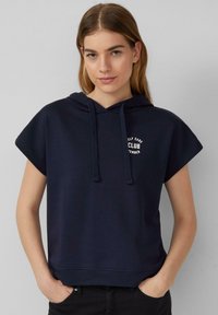 Námornícky modrý hoodie s krátkym rukávom a kapucňou, prednou kapsou a bielym textom "Self Care Club" na hrudi. Vyrobený z jemnej, štruktúrovanej tkaniny.
