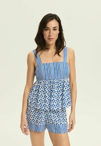 Niebieska i biała, w paski, bezrękawnik o rozkloszowanym kroju i geometrycznym wzorze, zestawiony z pasującymi szortami. Miękka tkanina, casualowy wygląd.