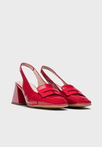 Chaussures slingback en cuir verni rouge avec un talon bloc triangulaire, dotées d'une large sangle décorative à l'avant et d'une texture lisse.
