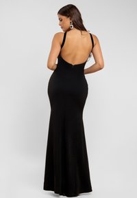 Sort, ærmeløs aftenkjole med dyb ryg, gulvlængde silhuet og en glat, tætsiddende tekstur med en diskret lynlås.