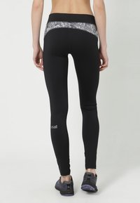 Czarne legginsy z teksturowanym szarym pasem, o dopasowanym kroju z logo na dolnej części nogawki. Gładki, elastyczny materiał.