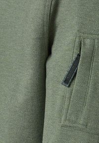 Groene sweatshirt van textuurstof, met een ritszak op de mouw. Het ontwerp is eenvoudig met een comfortabele pasvorm.