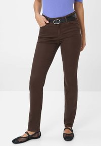 Jeans bruns ajustés avec une texture lisse, dotés d'un design classique à cinq poches et d'une ceinture noire avec une boucle en métal argenté.